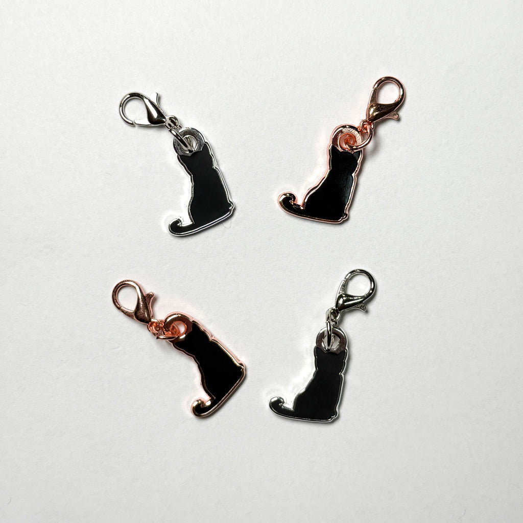 Four black cat-shaped charms with rose gold and silver accents on a white background