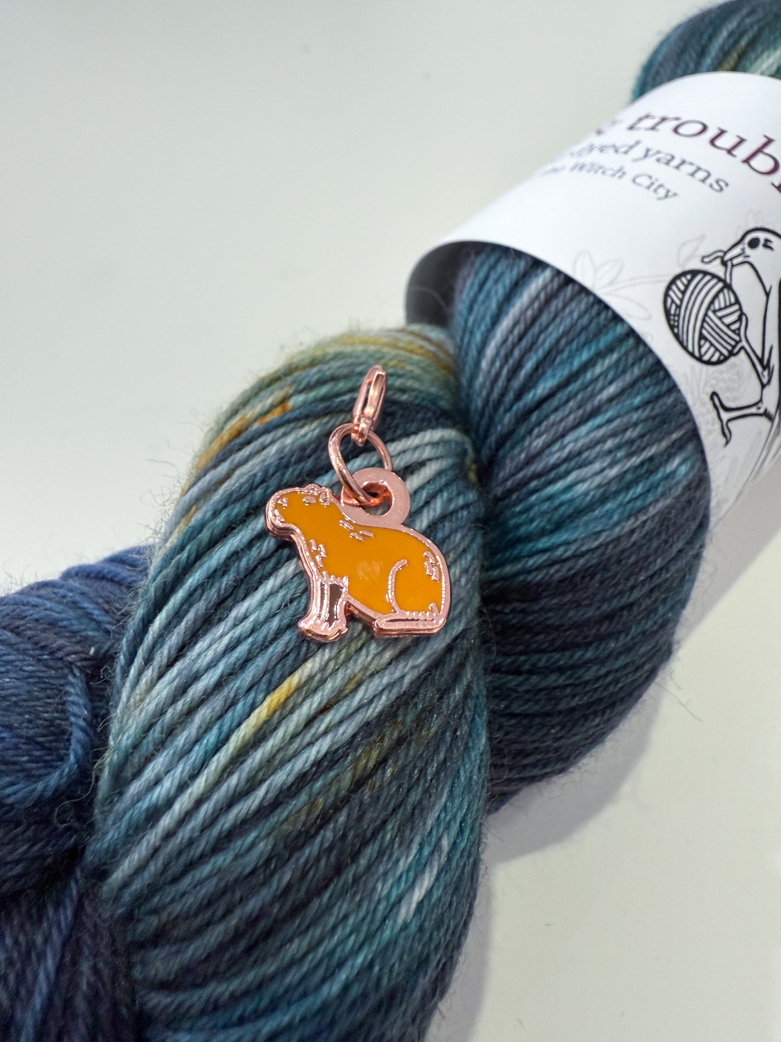 Yarn skein with a capybara charm on a white background