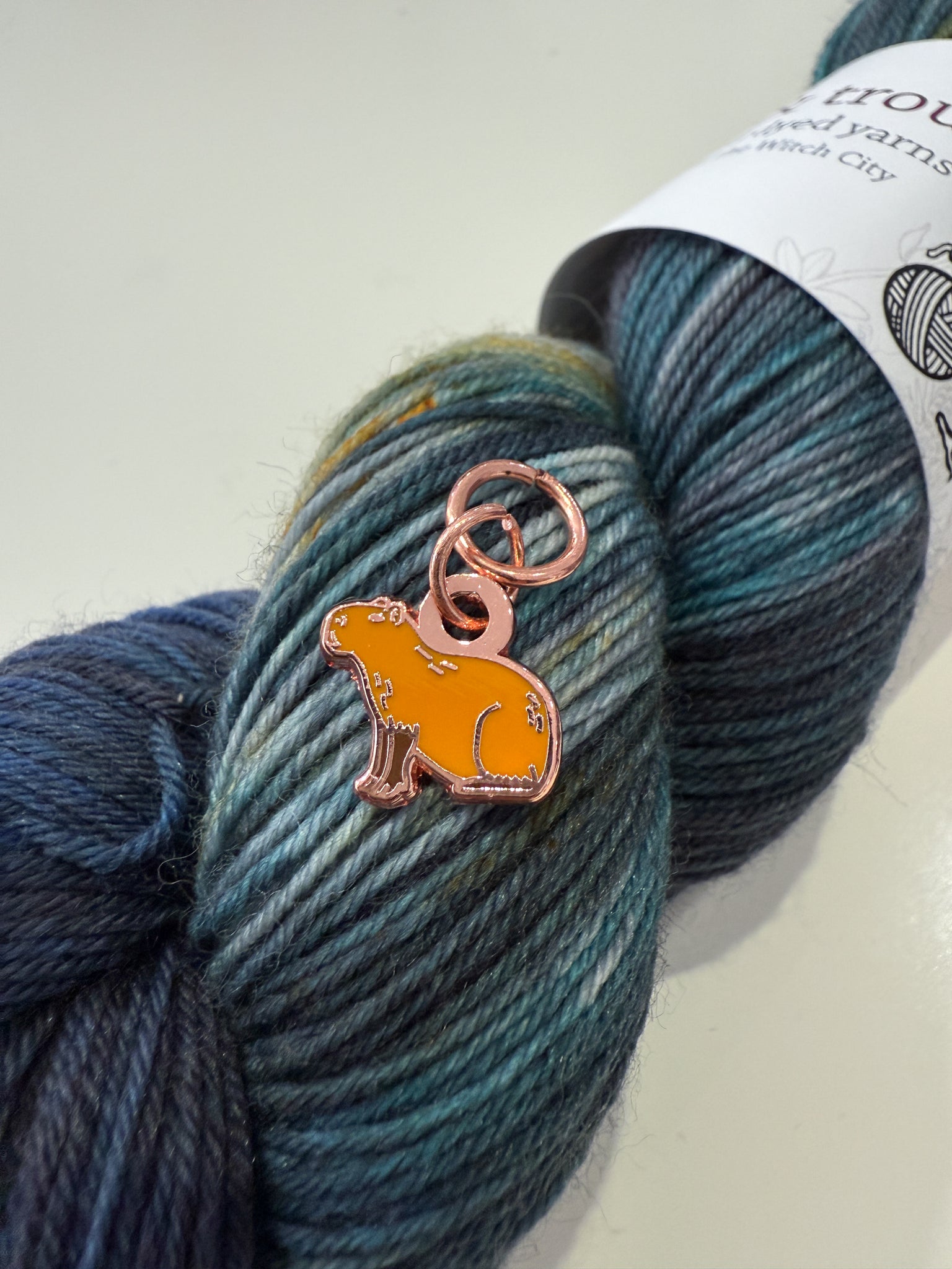 Yarn skein with a charm shaped like a capybara on a white background