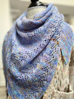 Blue knitted shawl on a mannequin with a blurred background