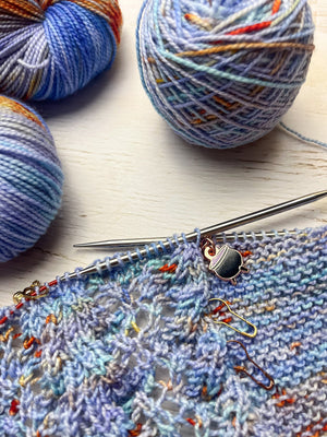 Knitted fabric with yarn and knitting needles on a wooden surface