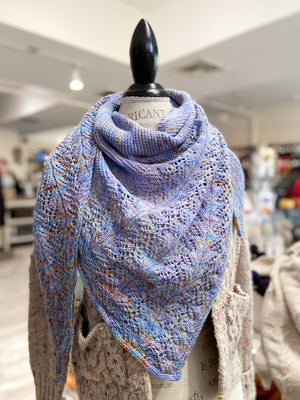 Blue knitted shawl on a mannequin in a store setting